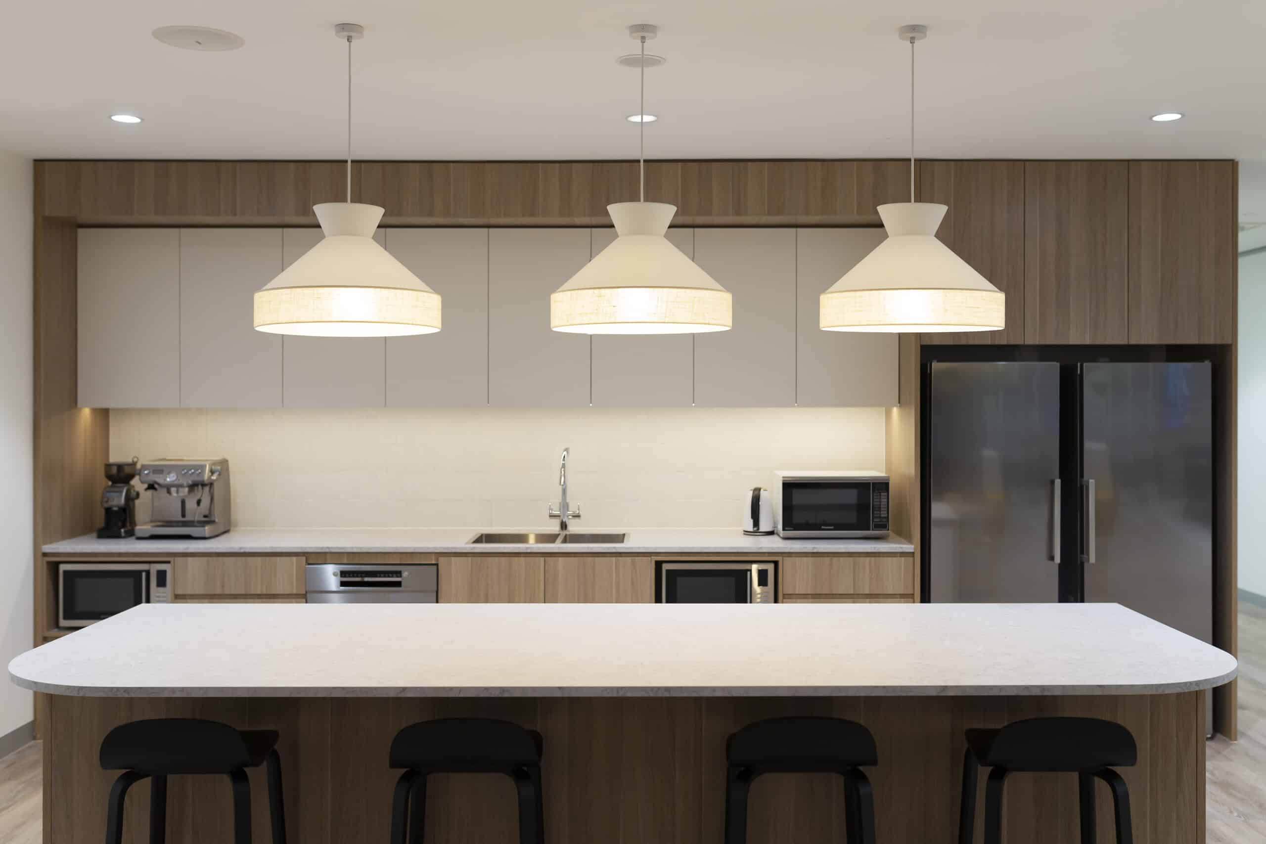 Contemporary office kitchen with a sleek design, featuring modern appliances, ample counter space, and a communal seating area.