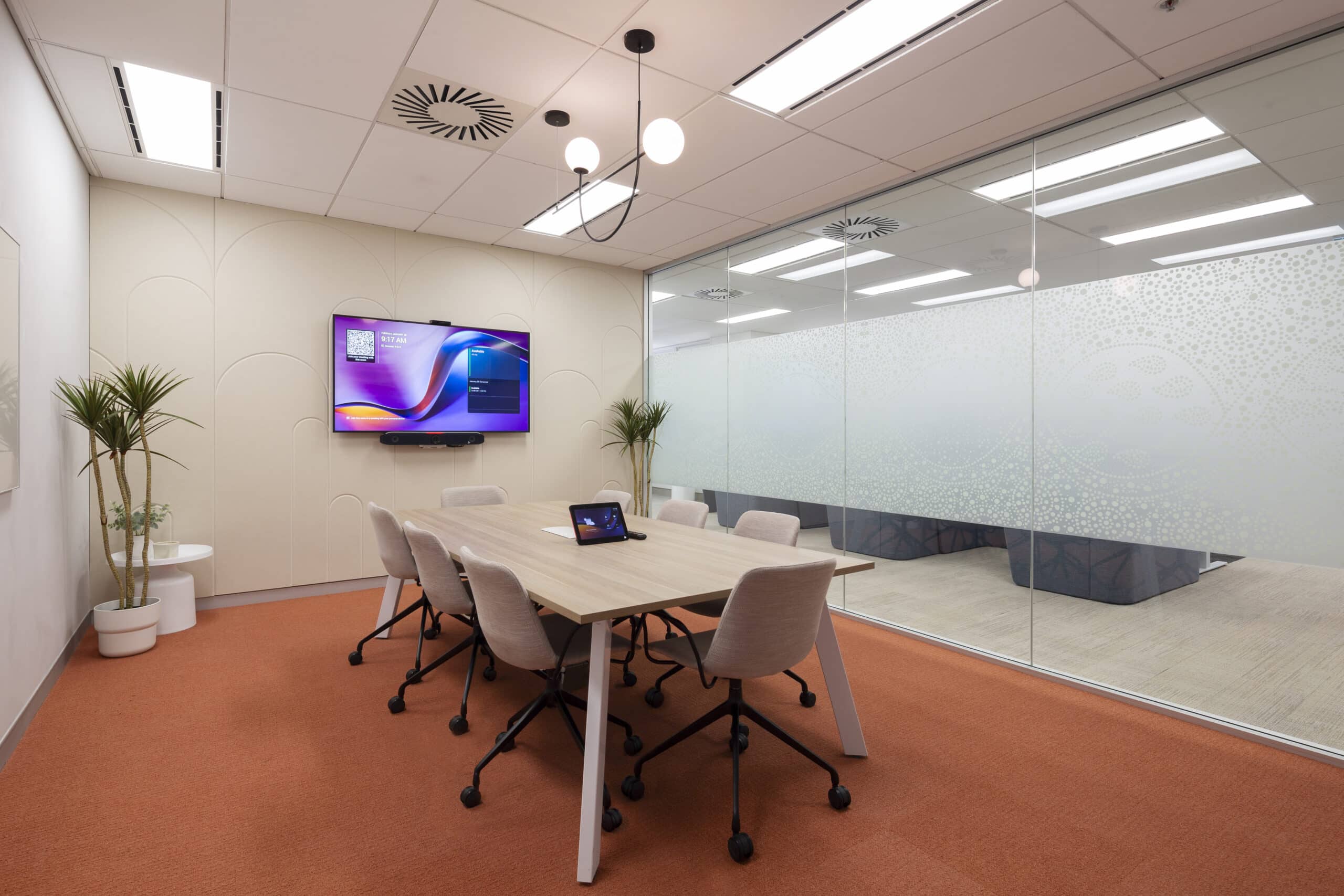 Modern meeting room with a spacious table, ergonomic chairs, and large windows, designed for collaboration in a professional setting.