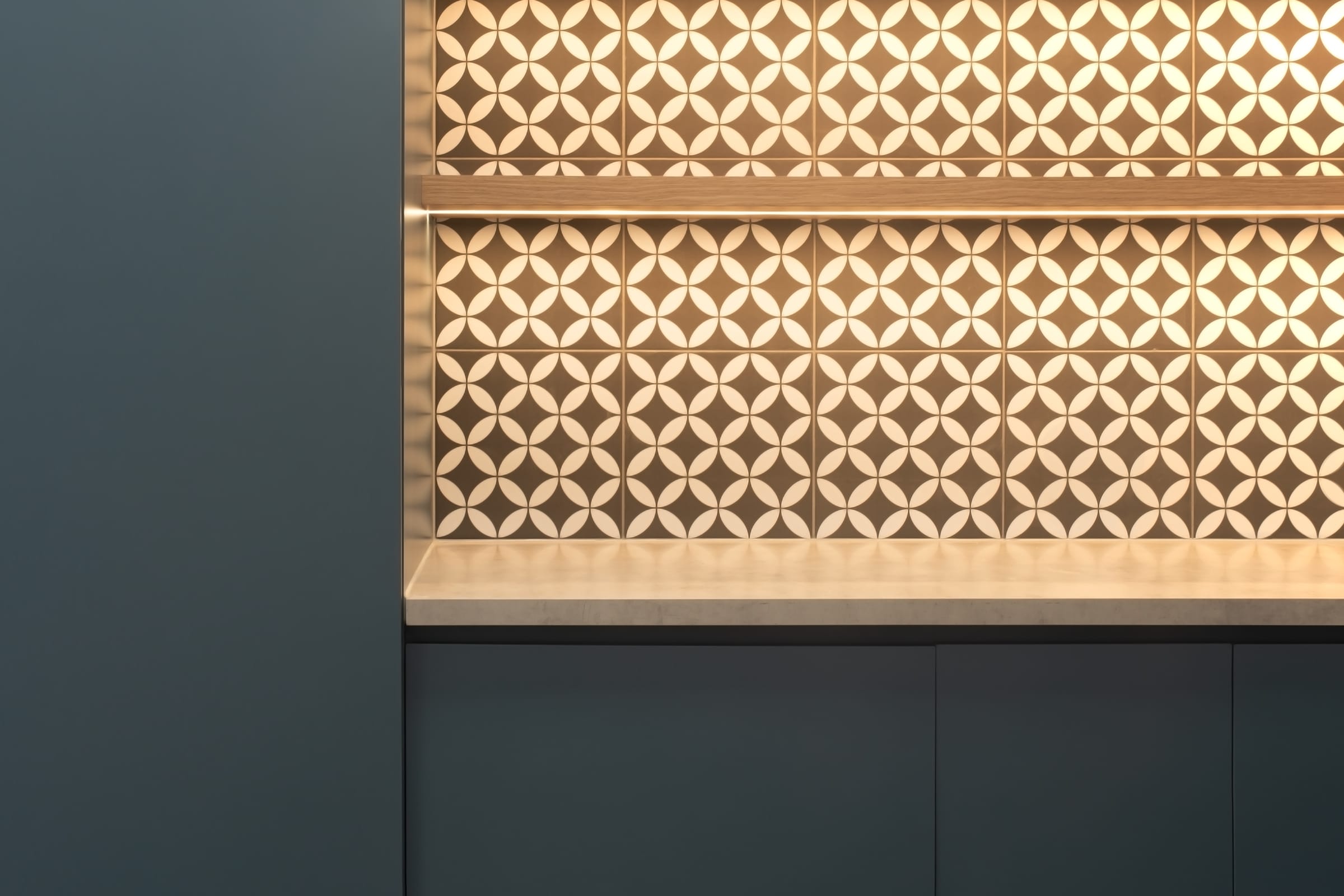 Close up of patterned tiled splashback with geometric motif and under shelf lighting in a staff kitchen.